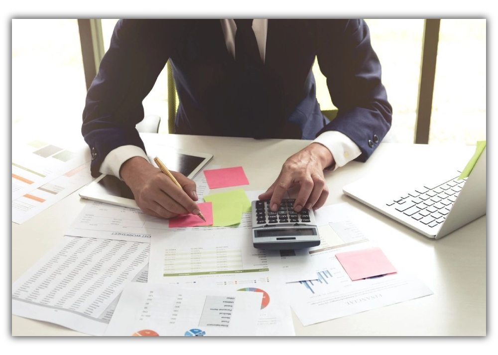 Person calculating finances with charts, sticky notes, and calculator.
